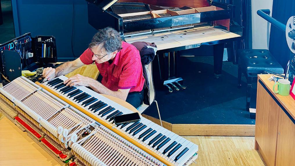 Man tuning baby grand piano.