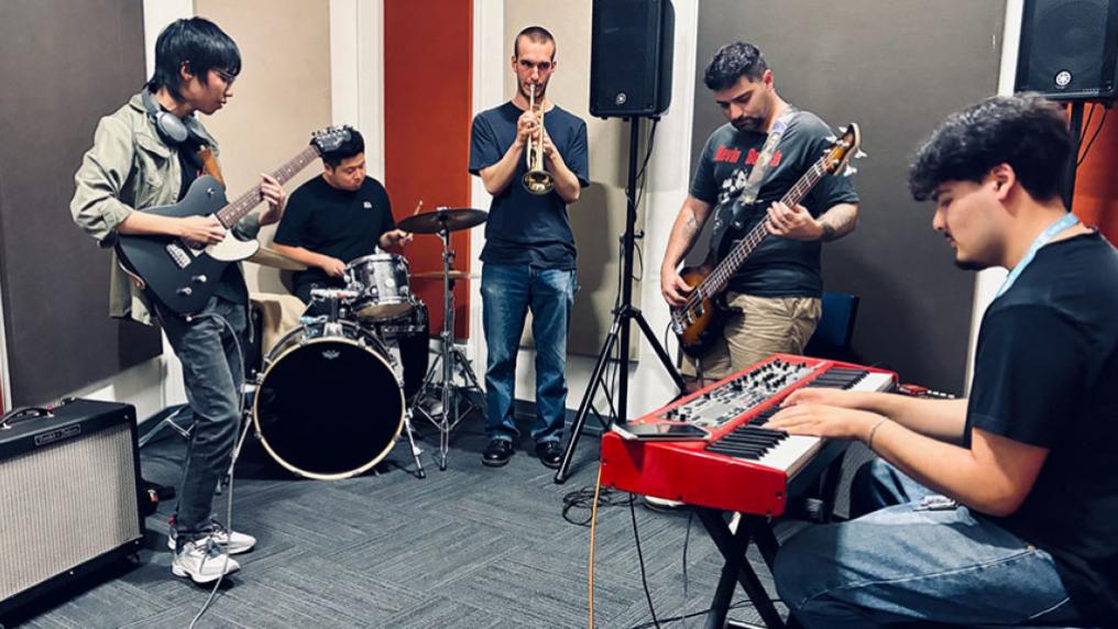 VU students playing musical instruments (keyboard, drums, guitars and trumpet) together.
