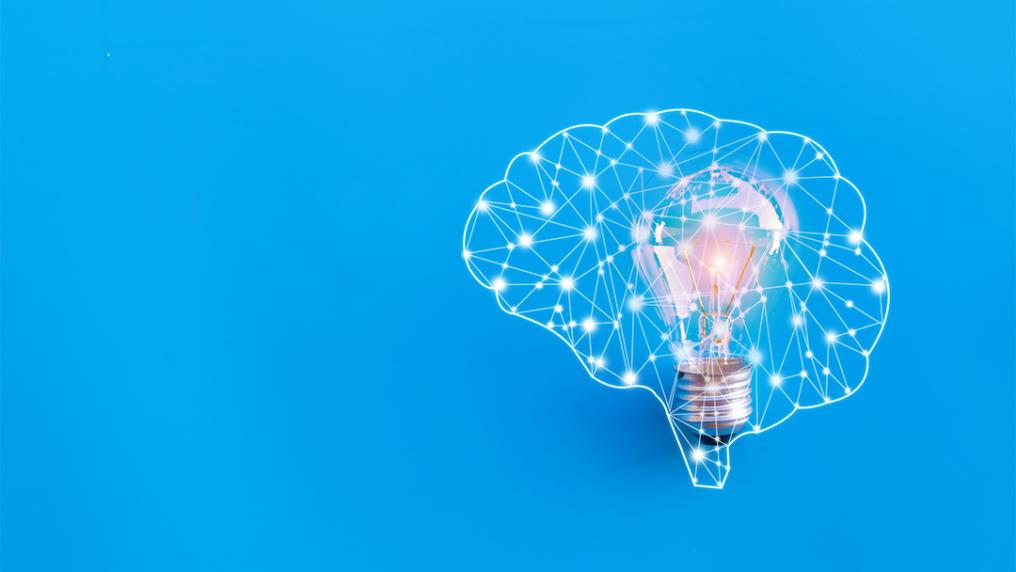 Image of the neural pathways of a brain with a lightbulb inside it, against a blue background.