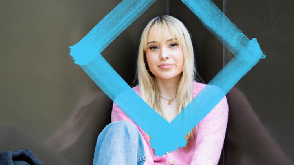 A student in a relaxed pose framed by the VU brand diamond