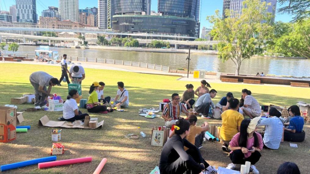 Groups of VU students on the South Bank park near Brisbane river. The students are doing various activities in groups.