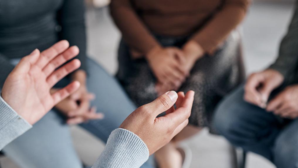 Group support session, person leading with outstretched hands.