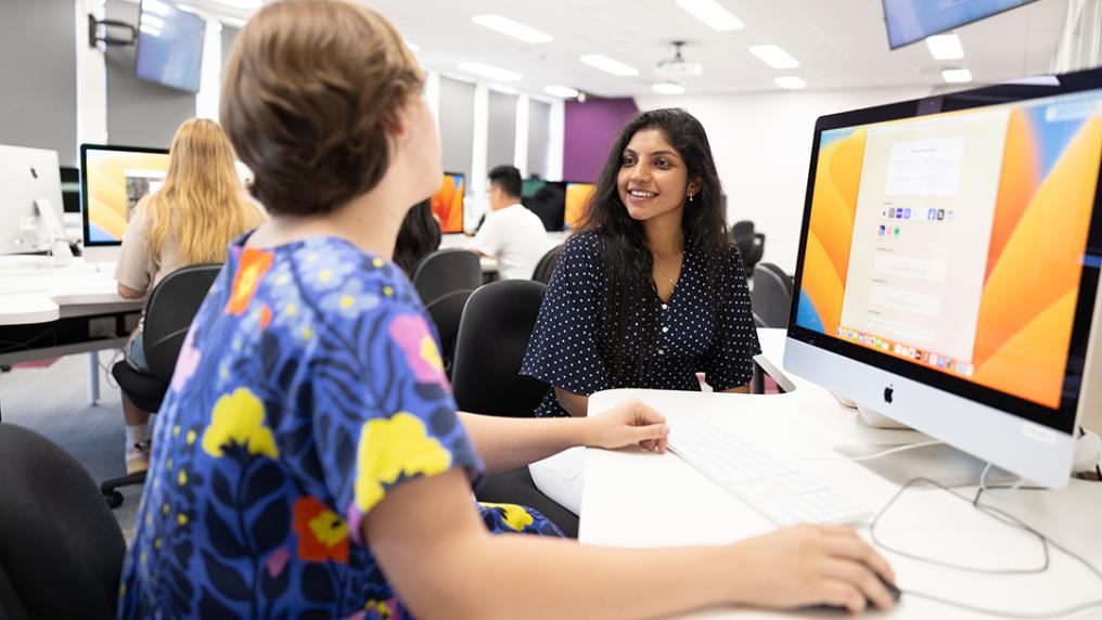 A group of students smile and interact in a modern computer lab