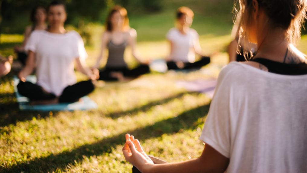 A group of people doing meditative yoga outdoors.
