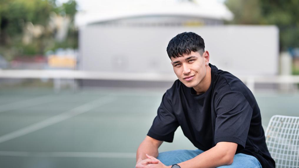 Student sitting on a chair next to the tennis courts at Footscray Park