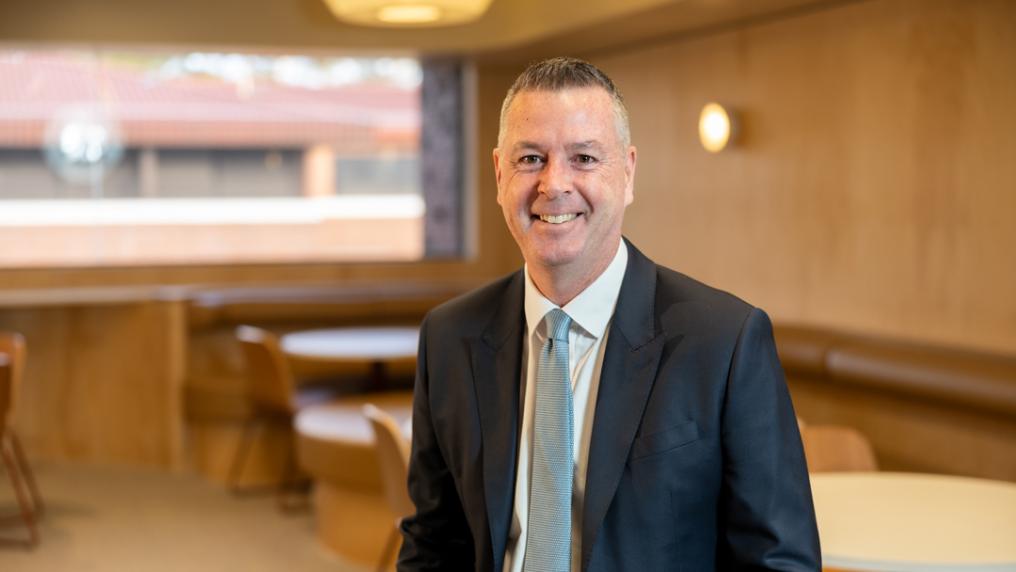 Professional looking man in suit smiles at the camera.