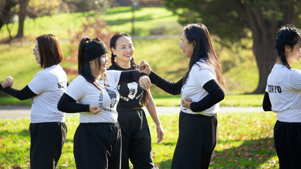 A group of martial art students practicing in a park with their teacher watching.