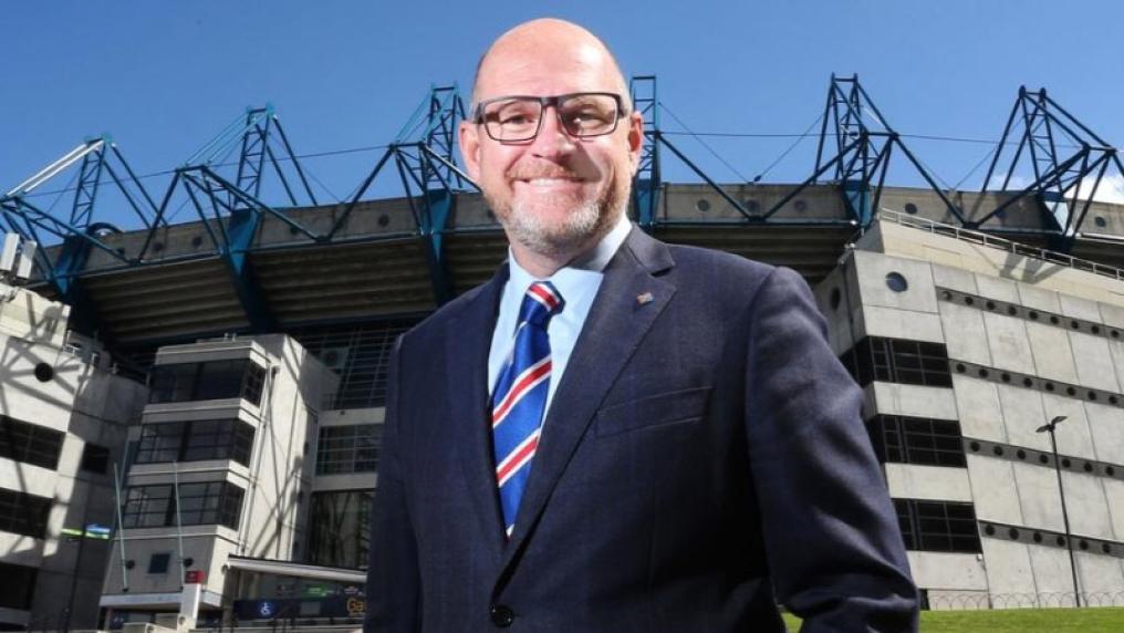 Smiling man in suit in front of sports stadium. 