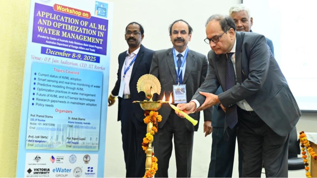 A group of people standing next to a standing poster. One person is lighting the lamp.