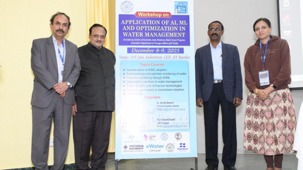 Four people standing for a photo in front of an event sign