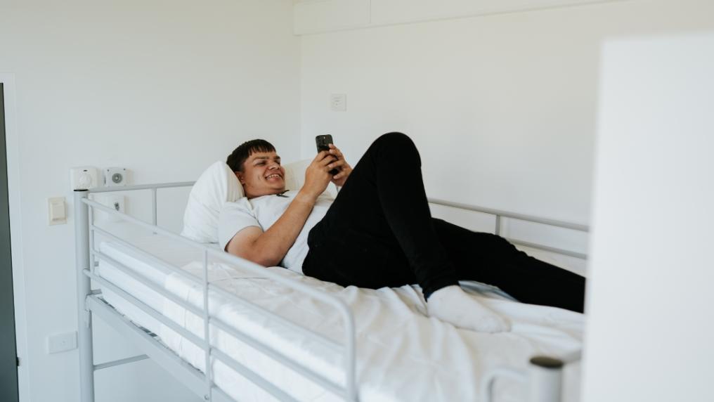 Altitude Hotel research participant lies in bed on phone