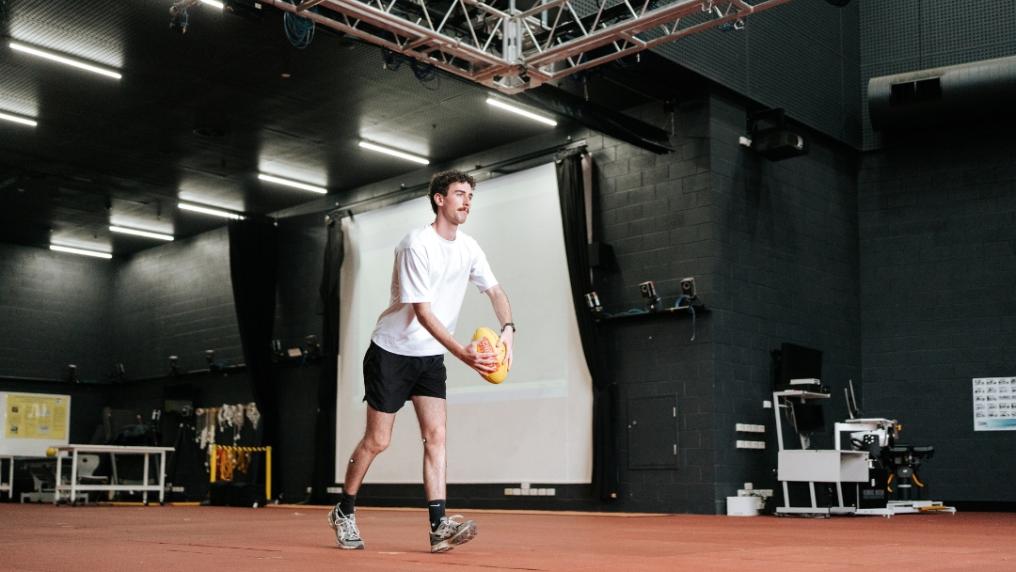 Student kicks a football in the biomechanics lab