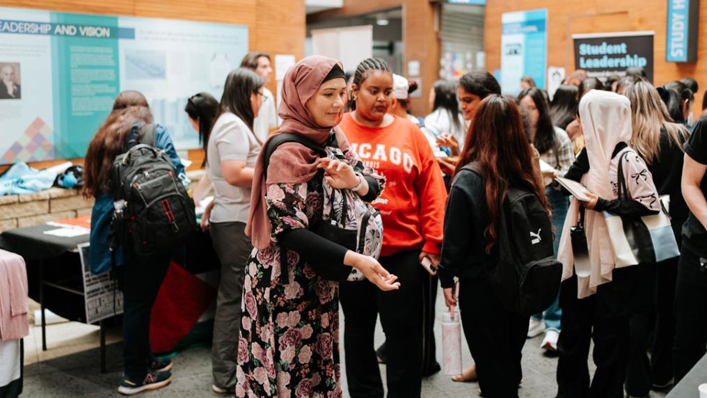 A large multicultural group of students interact with information stalls