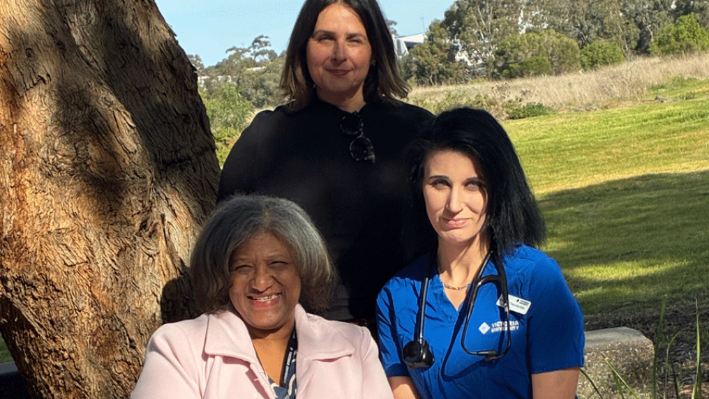 3 women, one in nurse's uniform, outside in the sunlight