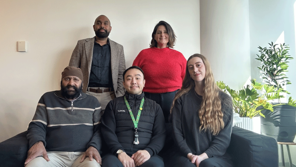 A multicultural group of adults in casual professional dress pose in a light, comfortable foyer