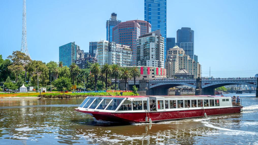 A small cruise ship on the yarra river. Melbourne City in the background.