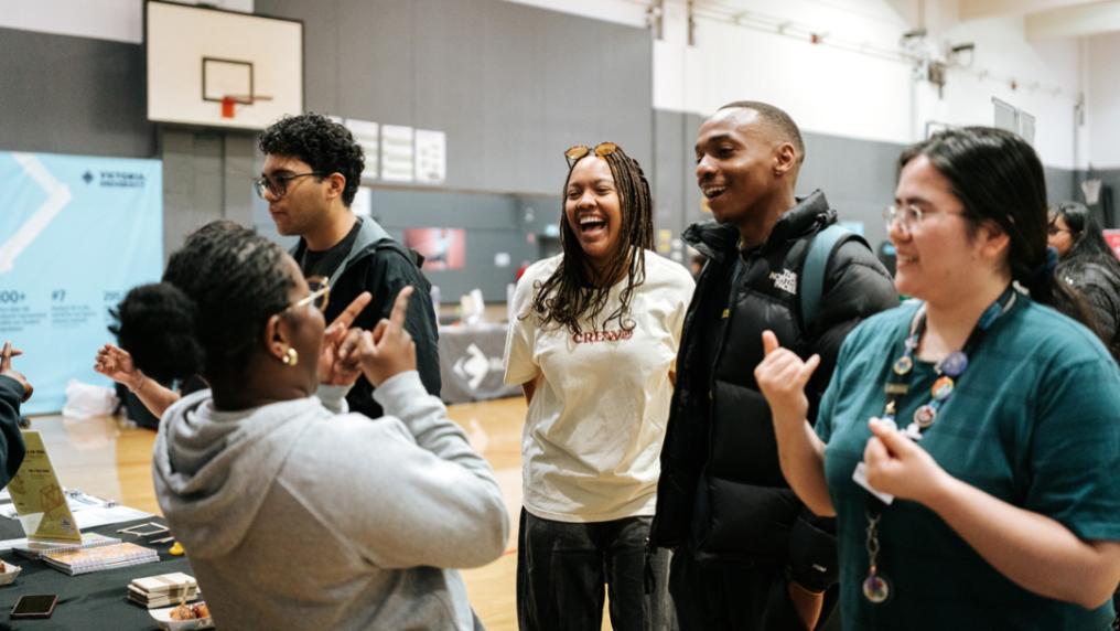 A group of happy, relaxed students at a casual event in a large indoor baskeball courts