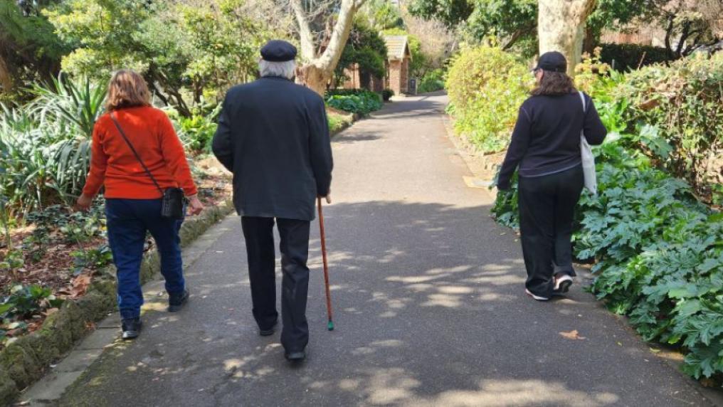 Three people walking through Footscray Park on a sunny day