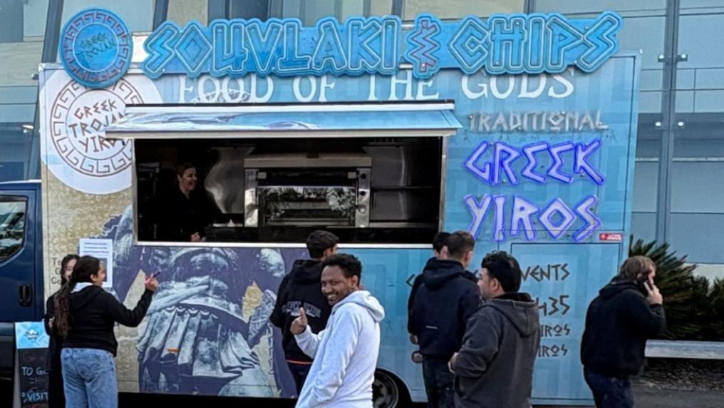 Greek food truck serving food to happy students.