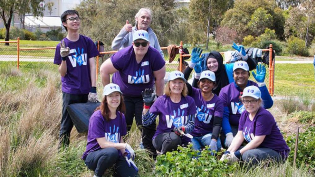 Students posing in grasslands at weeding working bee V4U Day project