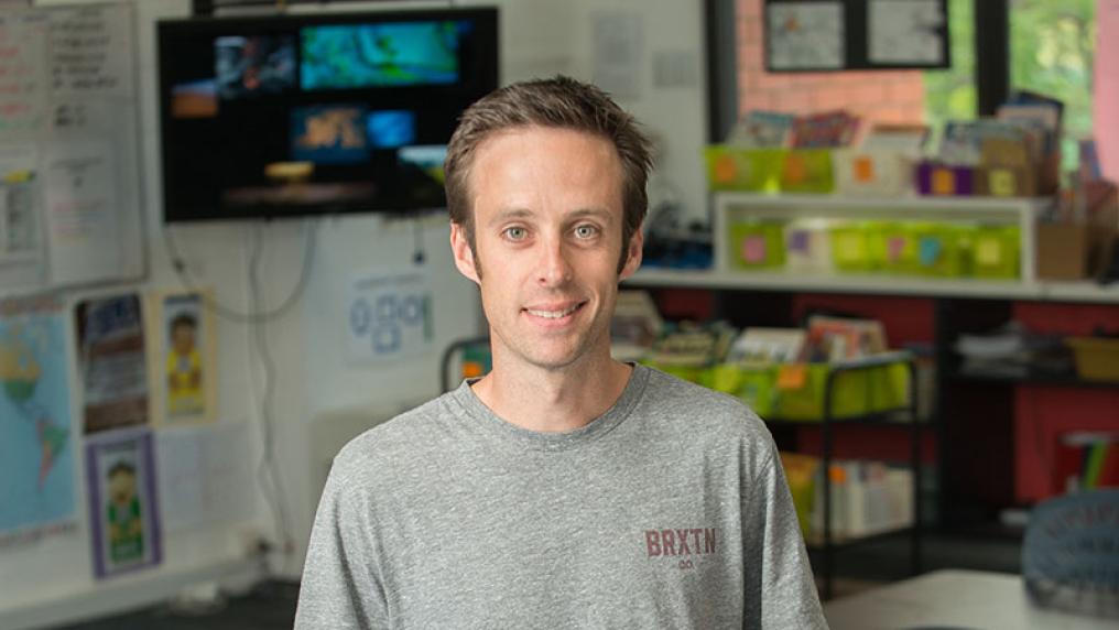 Ben Foster, past Bachelor of Education (P-12) student standing in a primary school classroom.