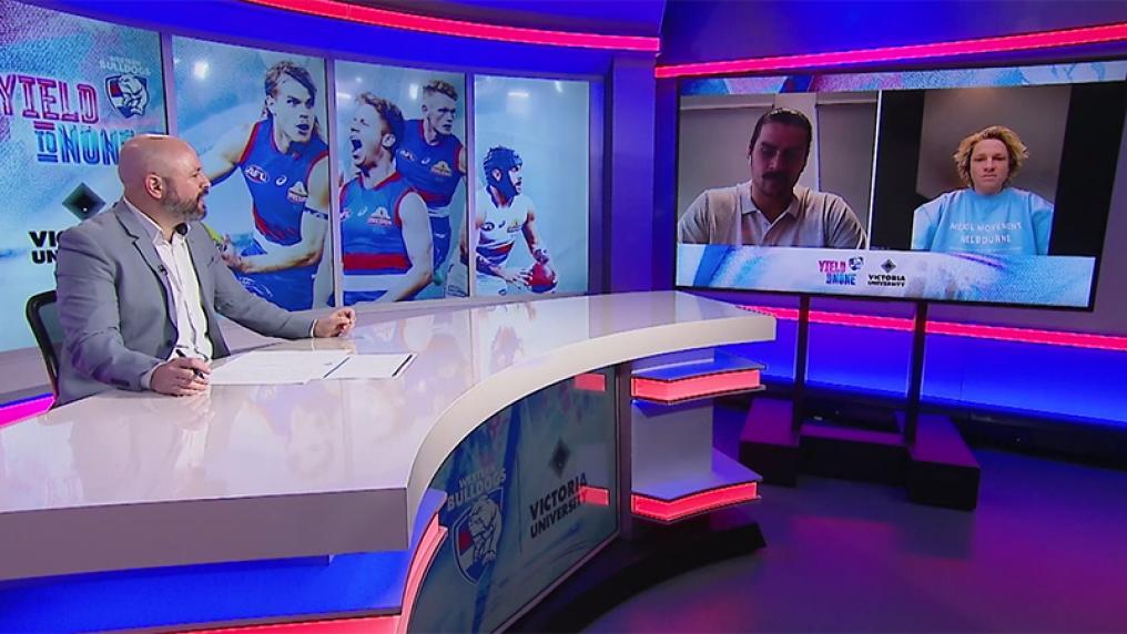 Male TV presenter at desk with Bulldogs colours and images talks to men on screen