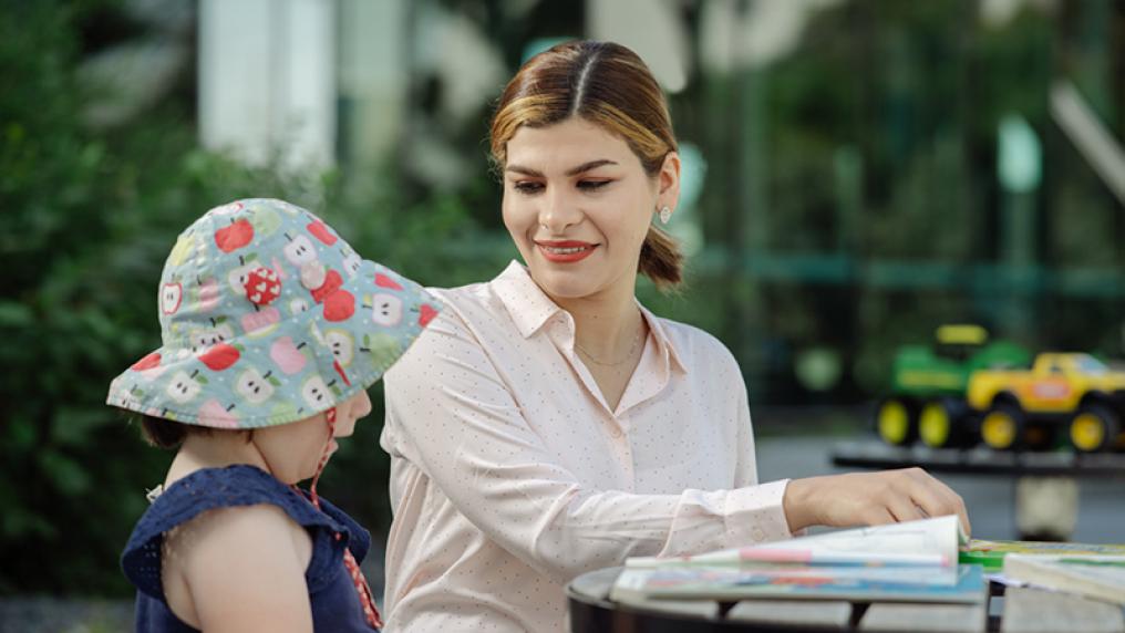 Early childhood teaching student smiles at kindergarten child