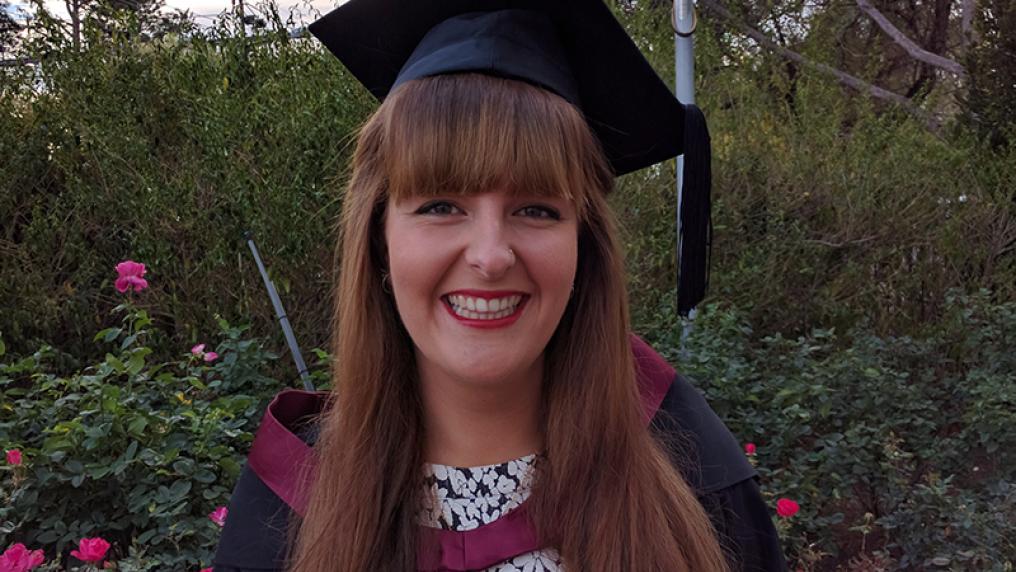 Rachel Pocock in a graduation cap and gown, outdoors
