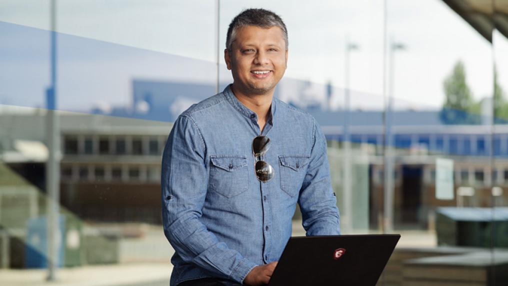 Man with computer, professionally dressed, smiling at camera