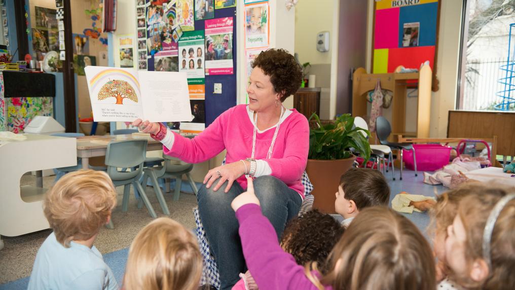  An early childhood teaching student reading to children in the classroom.