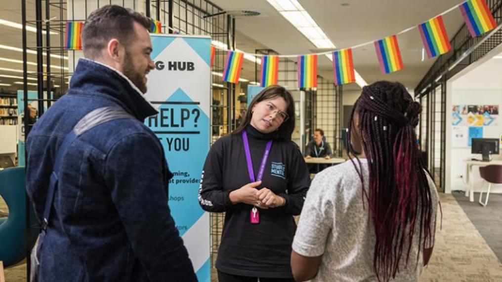A student mentor listens attentively to 2 students arriving at a drop-in session