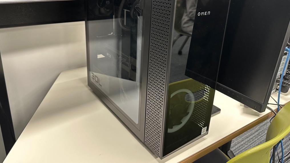 A computer tower sitting on top of a desk. The tower has the word "OMEN" on the front.