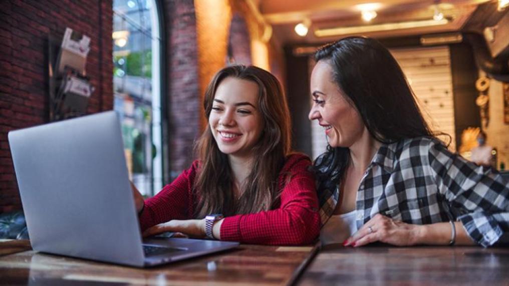 A parent and teenager looking at a laptop and planning their Open Day.