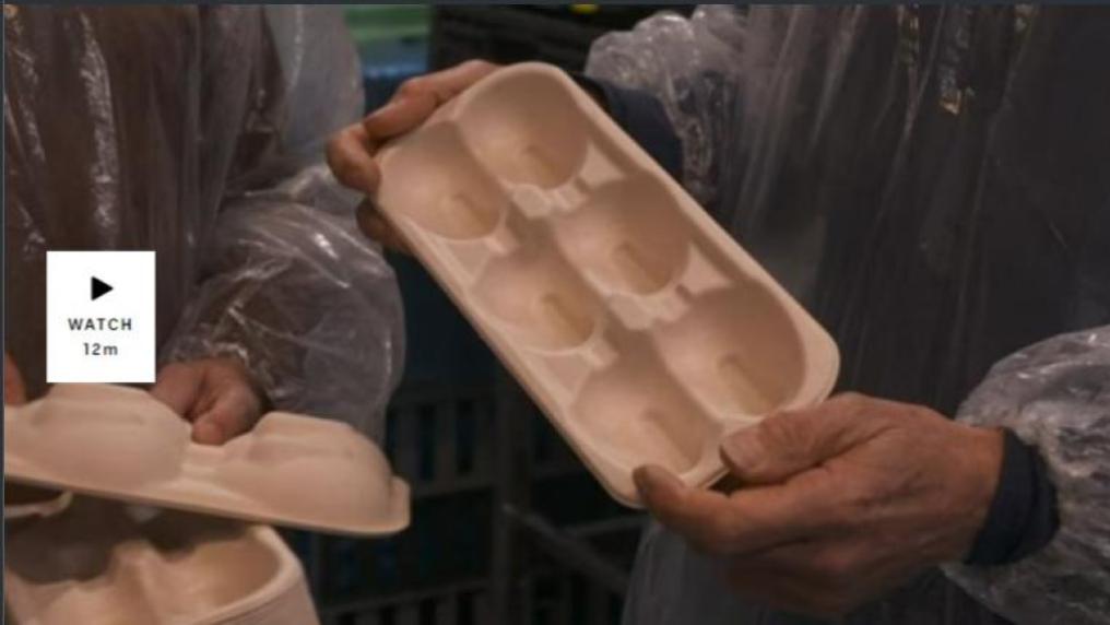 A video still of people's arms in plastic lab gear, holding packaging