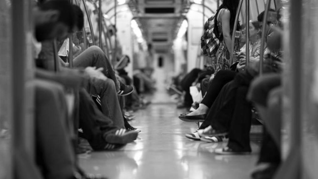 train showing passenger legs and a woman facing away with a backpack