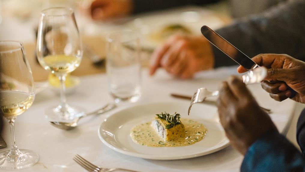 A formal, sophisticated dinner with glass of white wine served on a table with white cloth