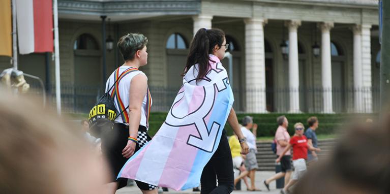 Two people walking with the transgender flag.